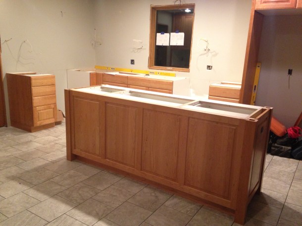 Island with gas range opening at left back. Sink below window and dishwasher to right of sink