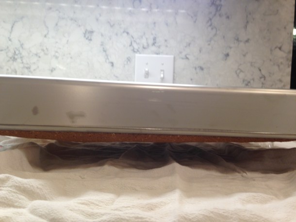 Turn cake pan upside down and balance with cups to hold cake above the counter. Cake does not fall out!